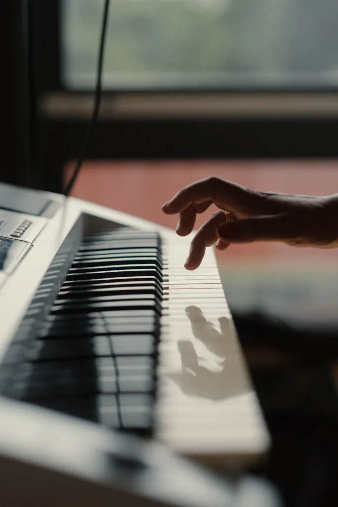 Eine Person spielt Klavier. Es sind nur das Instrument und eine Hand zu sehen.