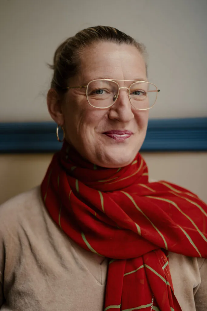 Eine Frau mit Brille schaut in die Kamera. Sie trägt einen roten Schal.
