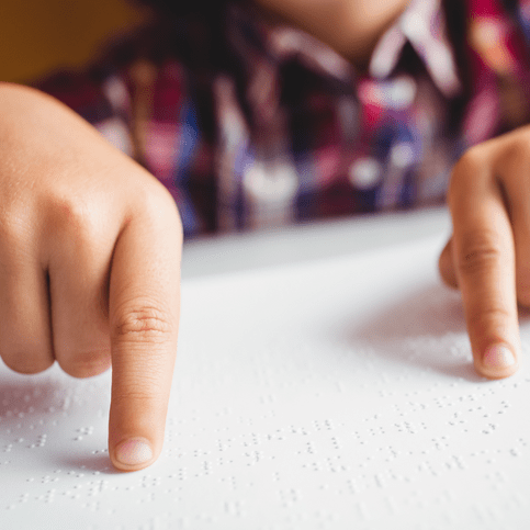 Finger eines Kindes, die Punktschrift ertasten.