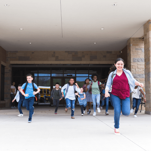 Kinder, die aus einer Schule rennen