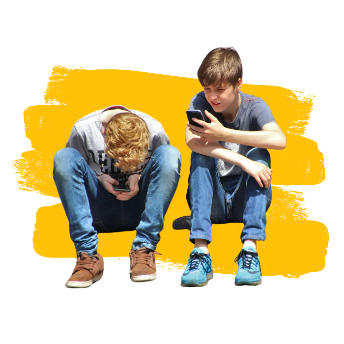 Zwei Jungen, die auf einer Borsteinkante sitzen und auf ihre Smartphones schauen.